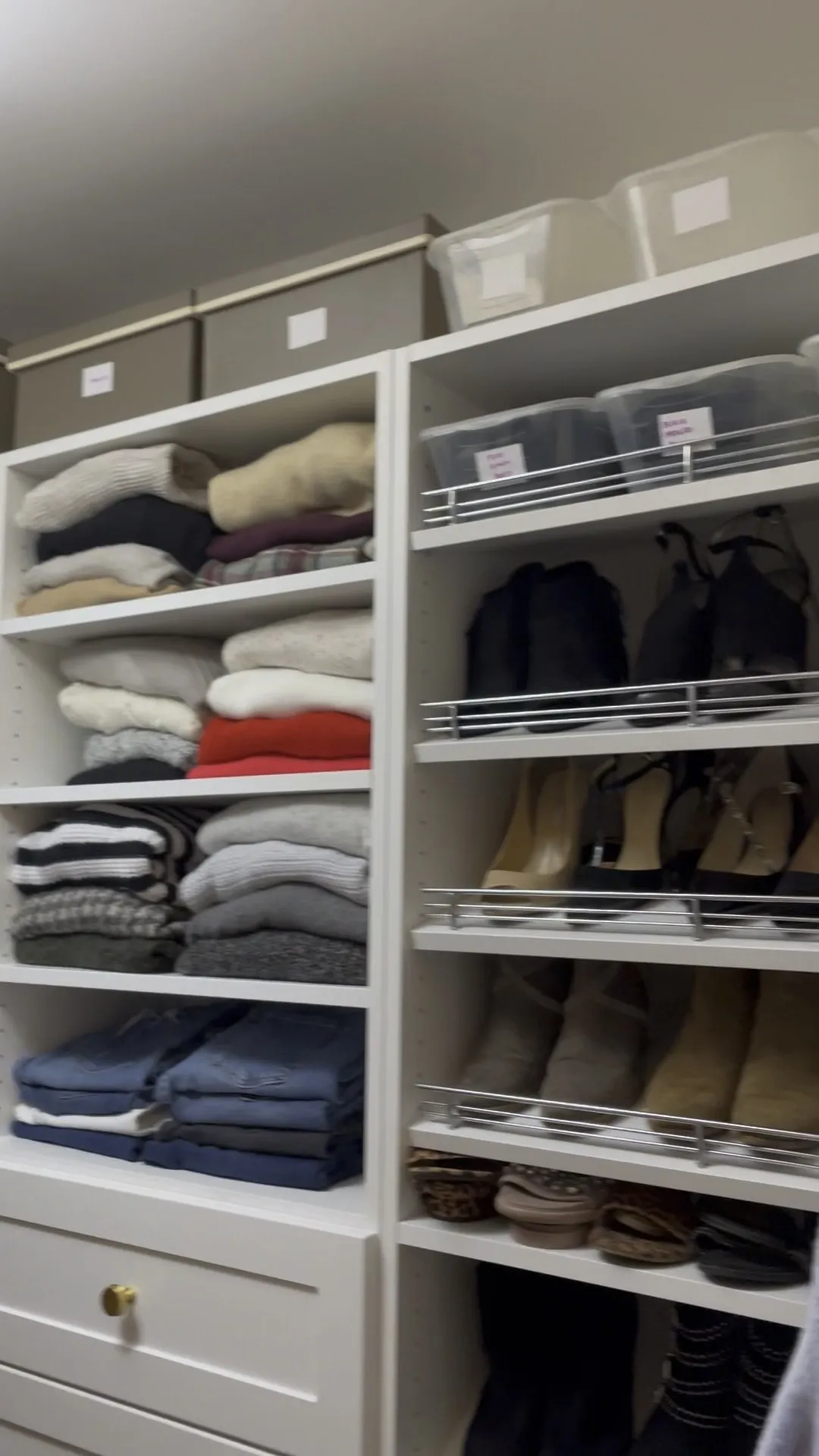 Folded sweaters and denim on open shelves beside shoe shelves