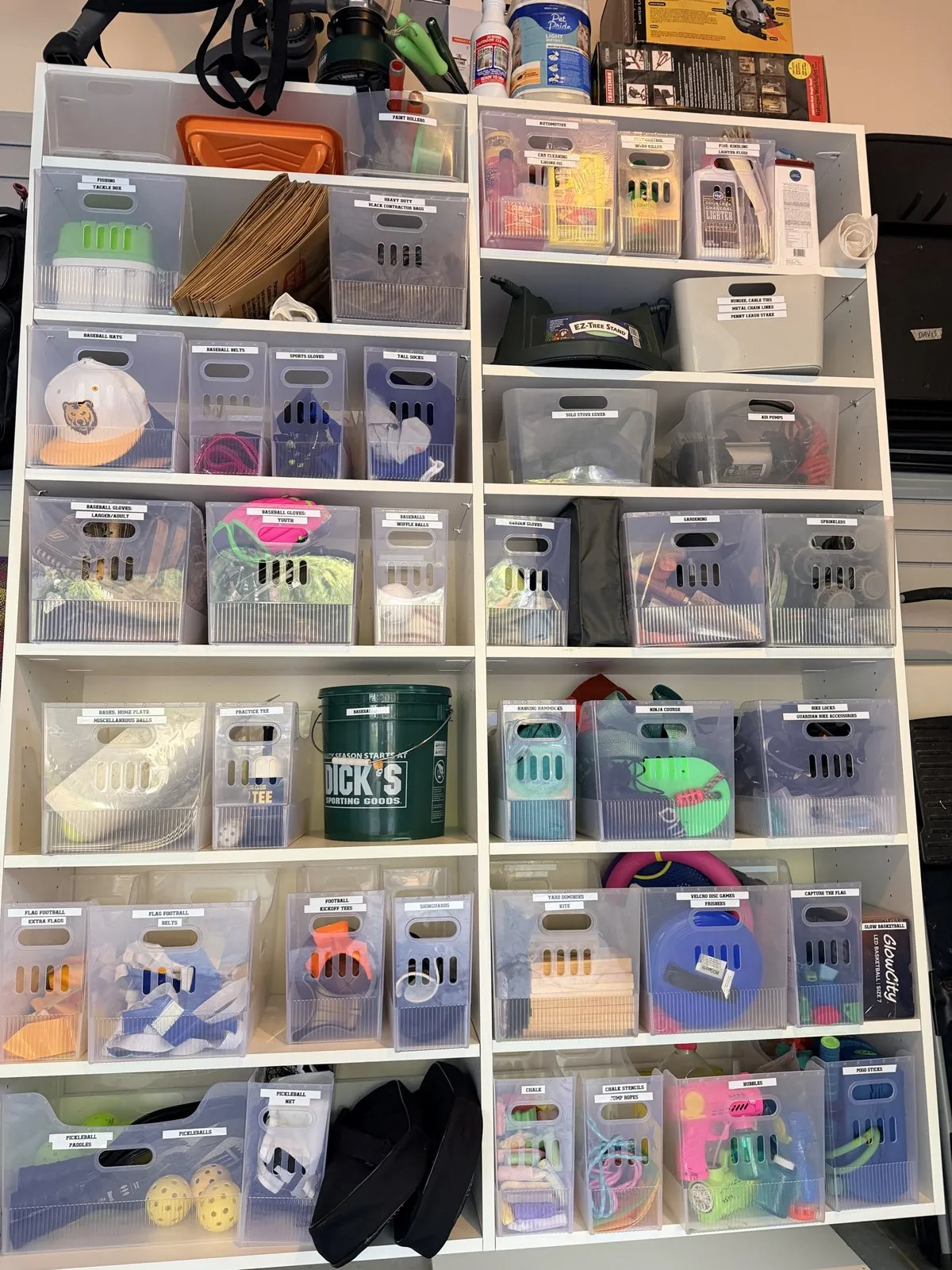Shelving wall of clear labeled bins for sports gear, yard games and tools