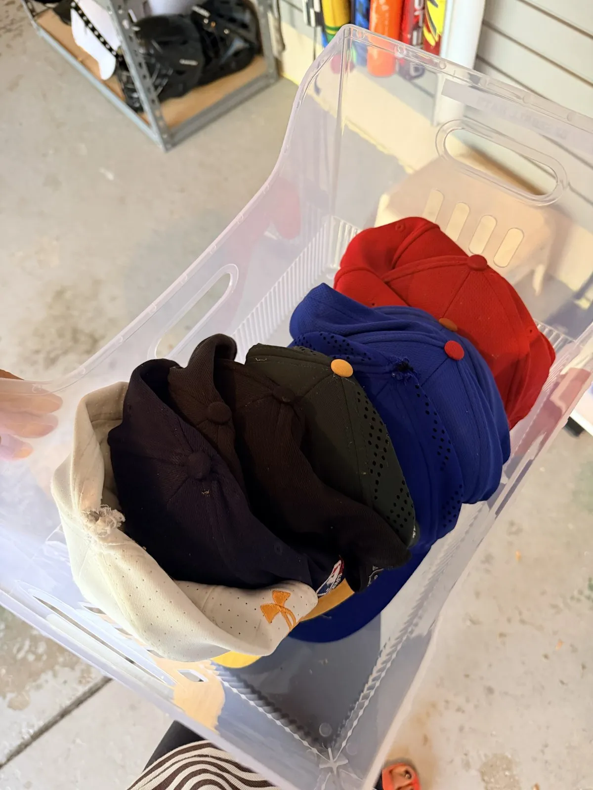 Clear bin of baseball caps stacked by color