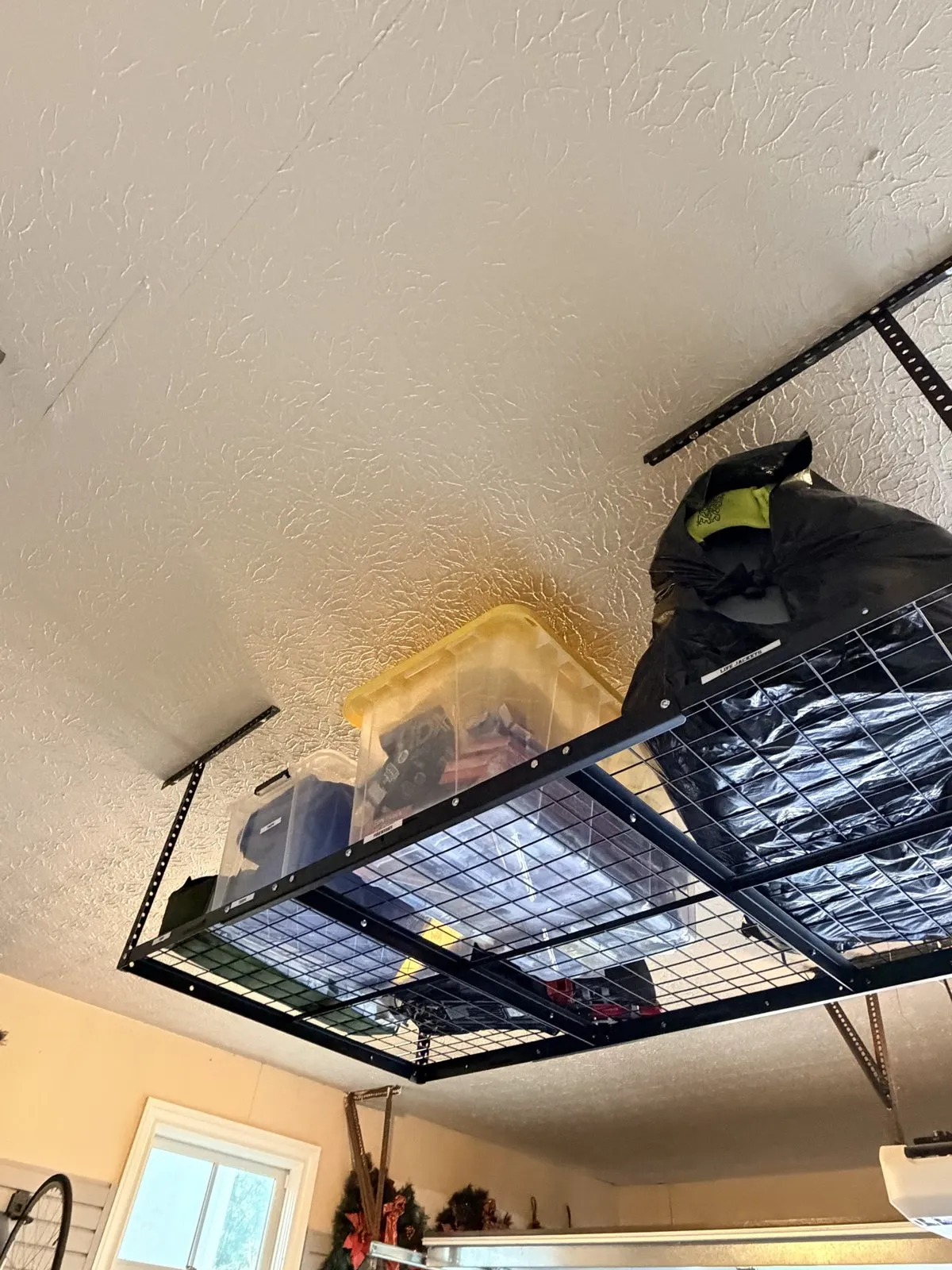 Overhead ceiling rack holding labeled bins for seasonal items